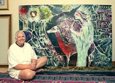 Inez sitting by an outdoor painting that she created called "Stroll Through Tuscany".