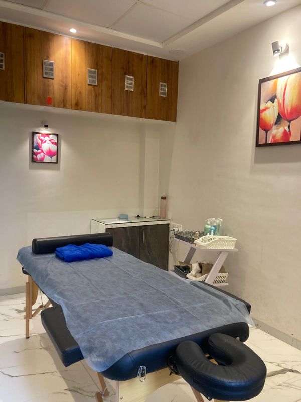 A clean massage room with a massage table and floral paintings.