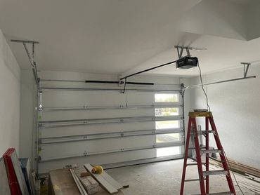 A garage with a newly installed garage door and a red ladder.