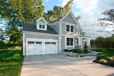 Modern two-story house with gray siding and white trim in a lush green setting.