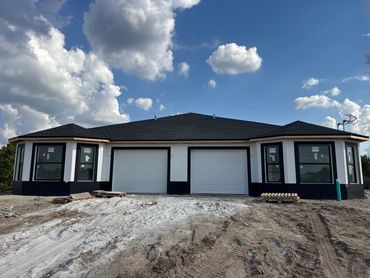 Newly constructed duplex house with black and white exterior under a blue sky.
