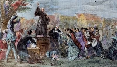 A historical scene of a man preaching to a crowd in an old village.