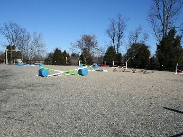 Sand/bluestone riding arena with jumps.