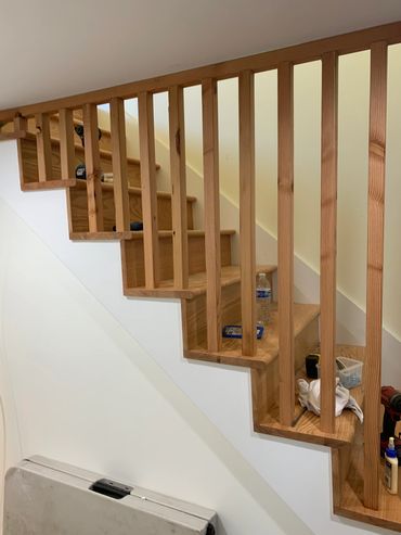 Wooden staircase with tools and a water bottle on the steps during renovation.