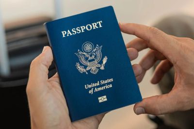 Hands holding a United States passport with a blue cover.
