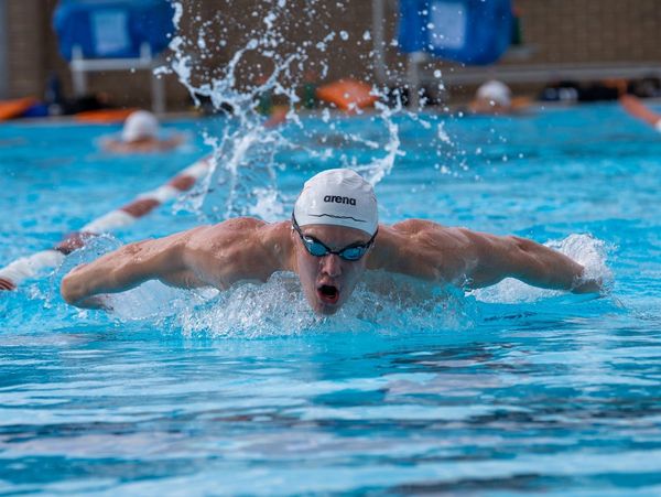 Swimmer performing butterfly stroke in pool.