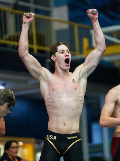 Swimmer celebrating victory with raised arms.