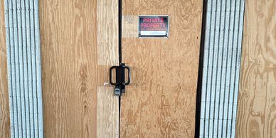 A locked wooden door with a Private Property. Board up and secure property. Includes winterization of property. Locksmith services.