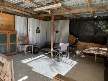 Rustic outdoor seating area with folding chairs and corrugated metal walls.