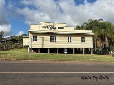 Historic Hivesville Hall building under a partly cloudy sky.