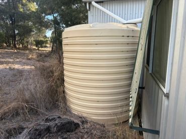 Beige water tank next to a metal building.