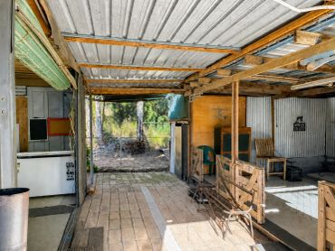 Rustic open-air shelter with wooden and metal structure.