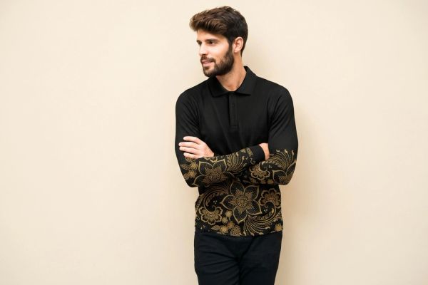 Man wearing a black shirt with gold floral batik designs.