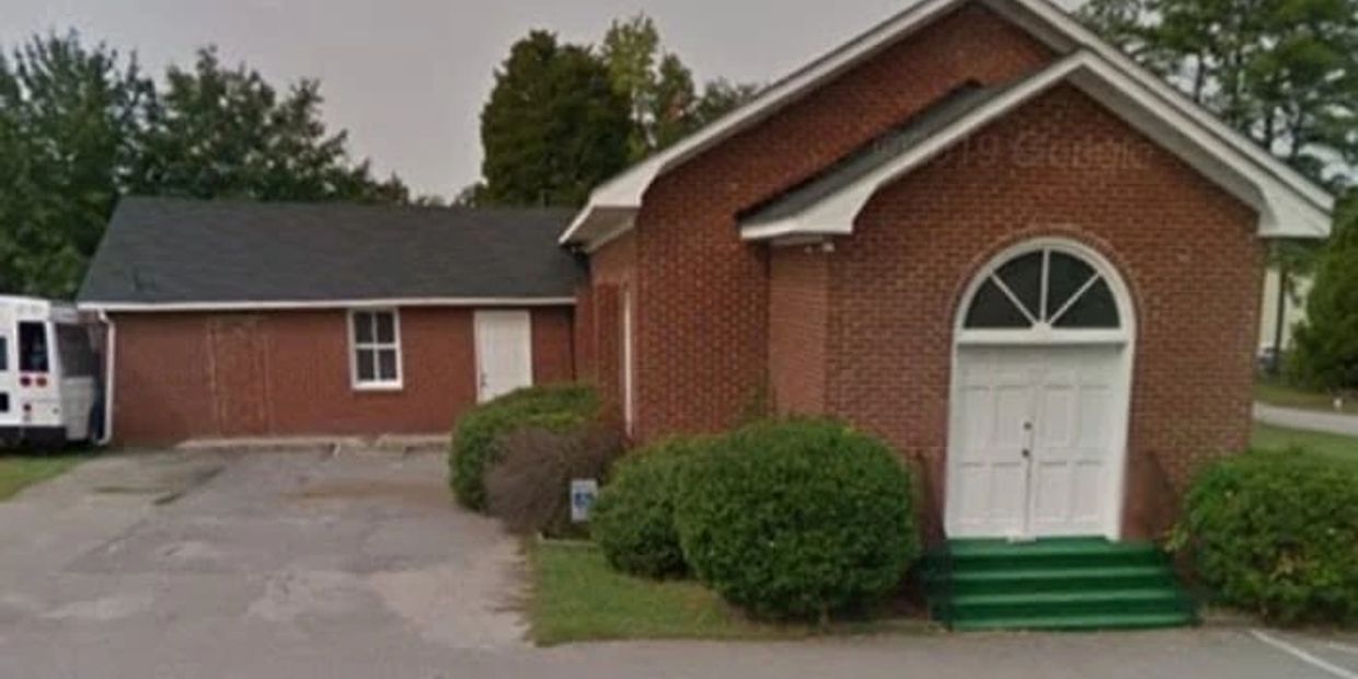 Small brick church with white doors and green steps.