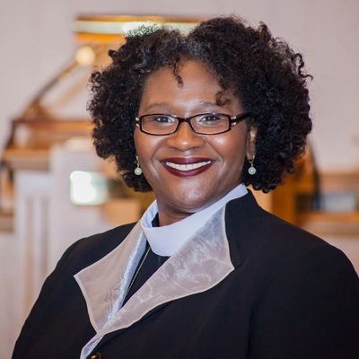 Smiling woman with glasses in formal attire.
