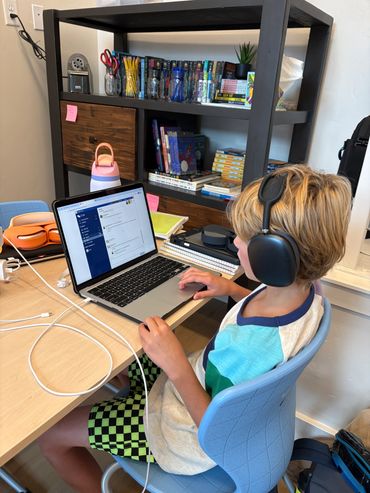 Young boy with headphones using laptop at a desk.