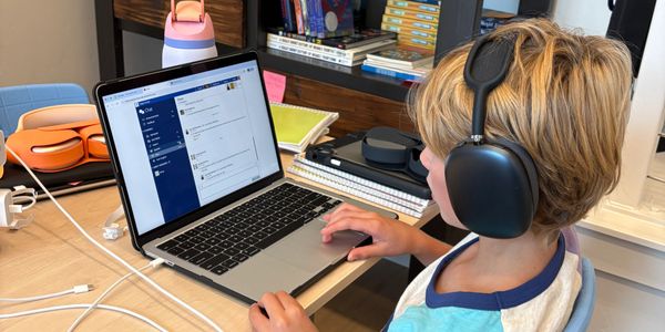 Young boy with headphones using laptop at a desk.
