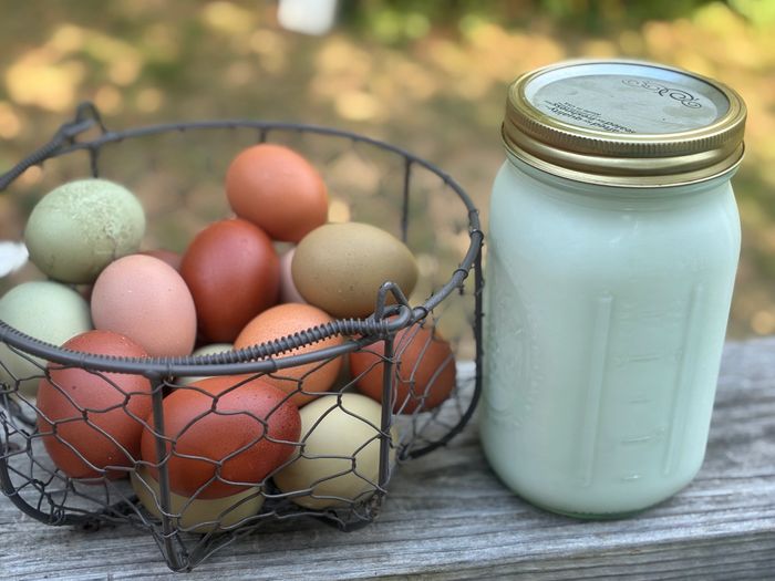 Basket of mixed eggs next to a glass jar of milk.