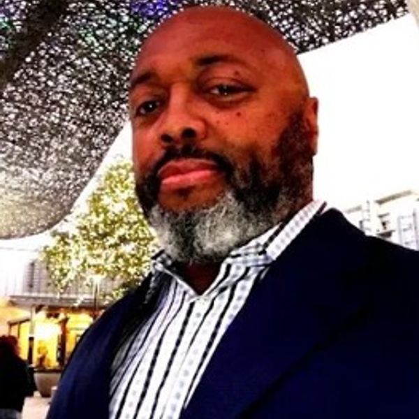 Man with a beard wearing a suit jacket outdoors.