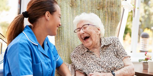 Nurse in blue uniform with happy elderly woman