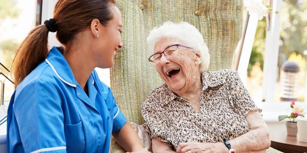 Nurse in blue uniform with happy elderly woman