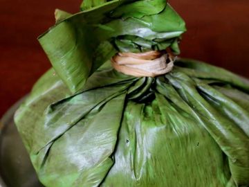 A bundle wrapped in fresh green leaves tied with a natural string.