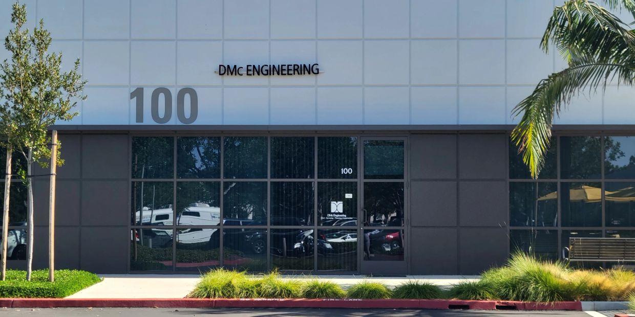 DMC Engineering building entrance with glass doors and large address number 100.