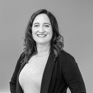 Smiling woman with wavy hair in a blazer.