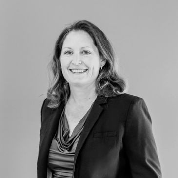 Smiling woman in business attire against a plain background.