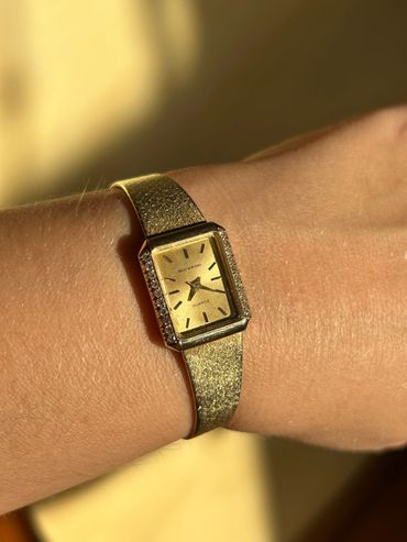 Elegant gold Movado wristwatch with a rectangular face and diamond accents.