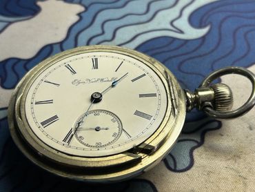 Close-up of an antique Elgin pocket watch with Roman numerals.