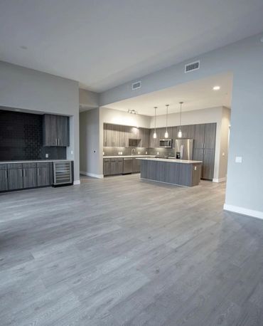 Modern kitchen with gray cabinets, island, and wood flooring.