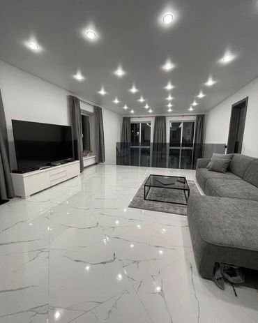 Modern living room with gray sofa, marble floor, and TV.