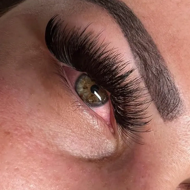 Close-up of beautifully done thick eyelash extensions and shaped eyebrows.