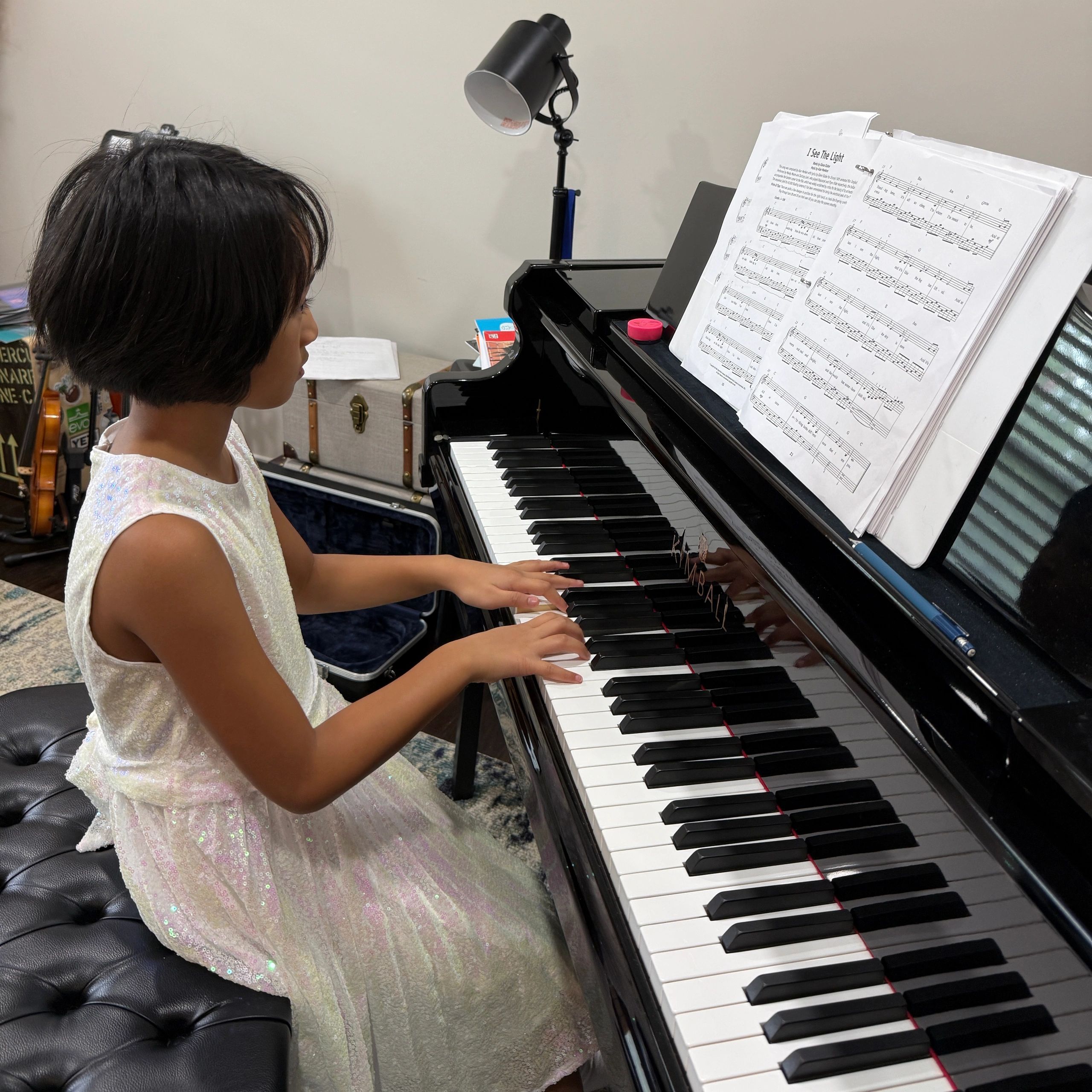 A young girl plays piano with sheet music.