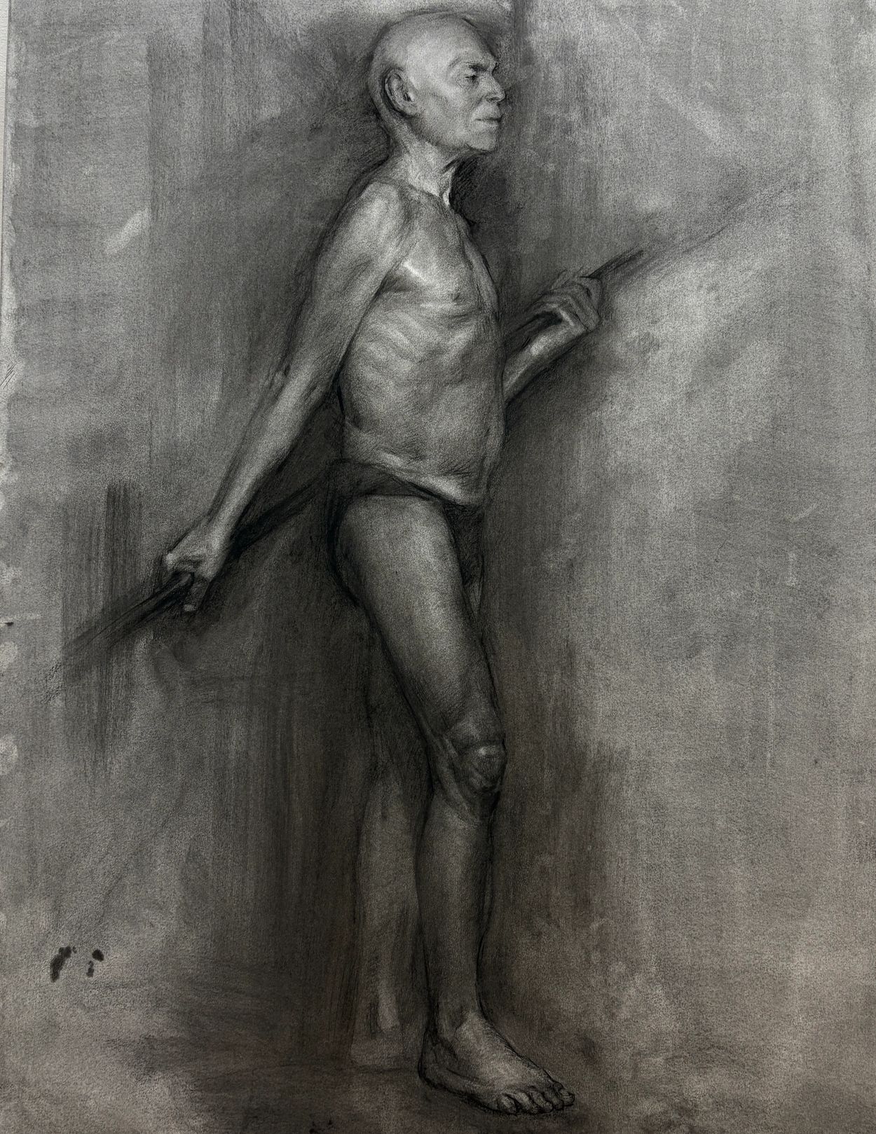 constructive academic drawing of old man standing and holding a staff, in charcoal on grey paper