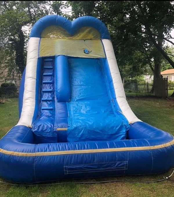 A blue and white inflatable slide in the grass.