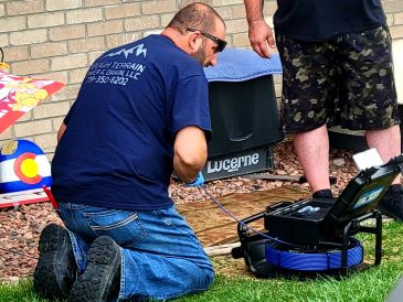 Man kneeling outdoors using specialized equipment.