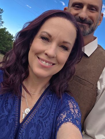 Smiling couple outdoors with blue sky background.
