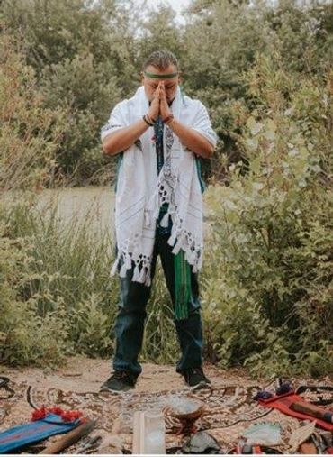 Spiritual healer praying over frankinsence and spiritual tools.
