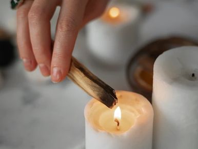 Palo Santo being lit on a white candle.