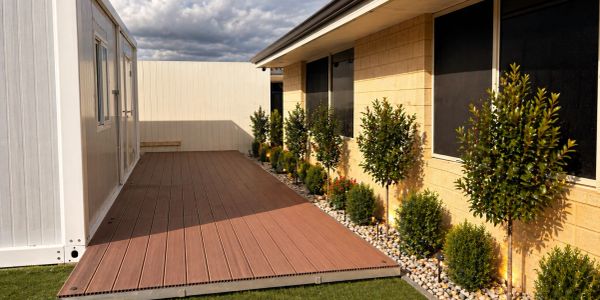 Modern backyard deck with greenery along house wall.