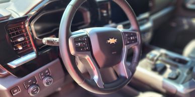 A freshly detailed steering wheel in a chevrolet truck or SUV.