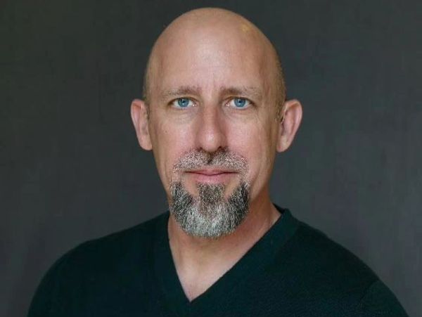 Portrait of a bald man with blue eyes and a salt-and-pepper goatee.