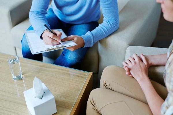 Therapist taking notes during a counseling session.