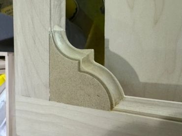 Close-up of a shaped molding profile fitted into the corner of a wood frame.