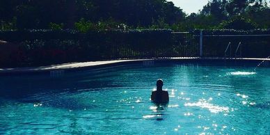 Person standing alone in a shimmering pool at dusk.