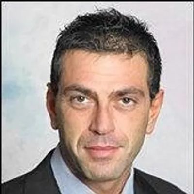 Professional headshot of a man in a suit with a neutral expression.