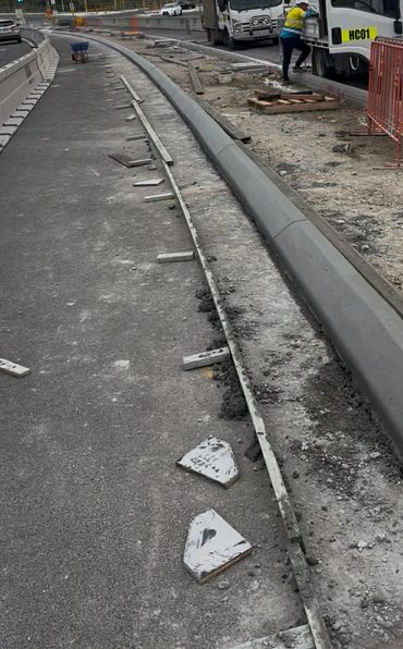 Road construction with workers and trucks on a cloudy day.