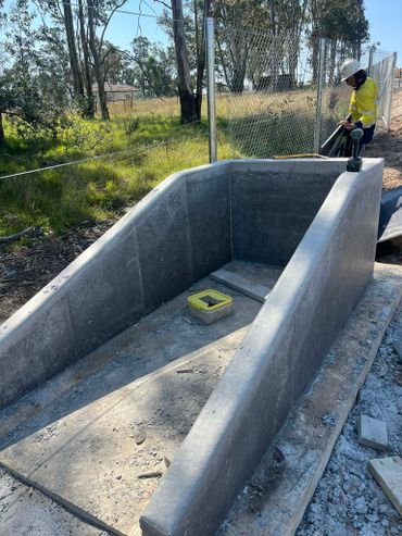 Construction site with a concrete structure and worker in safety gear.